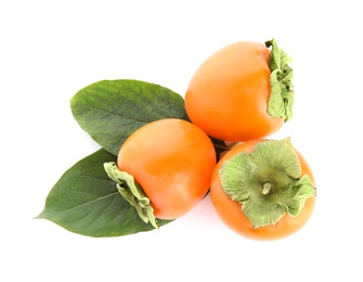 Photo of Delicious persimmons and green leaves isolated on white, top view