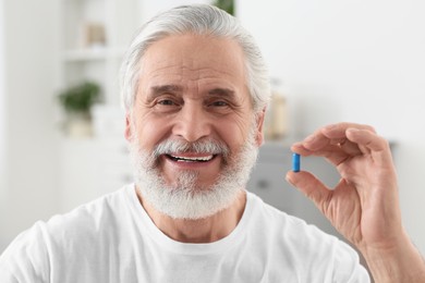 Photo of Handsome senior man with pill on blurred background