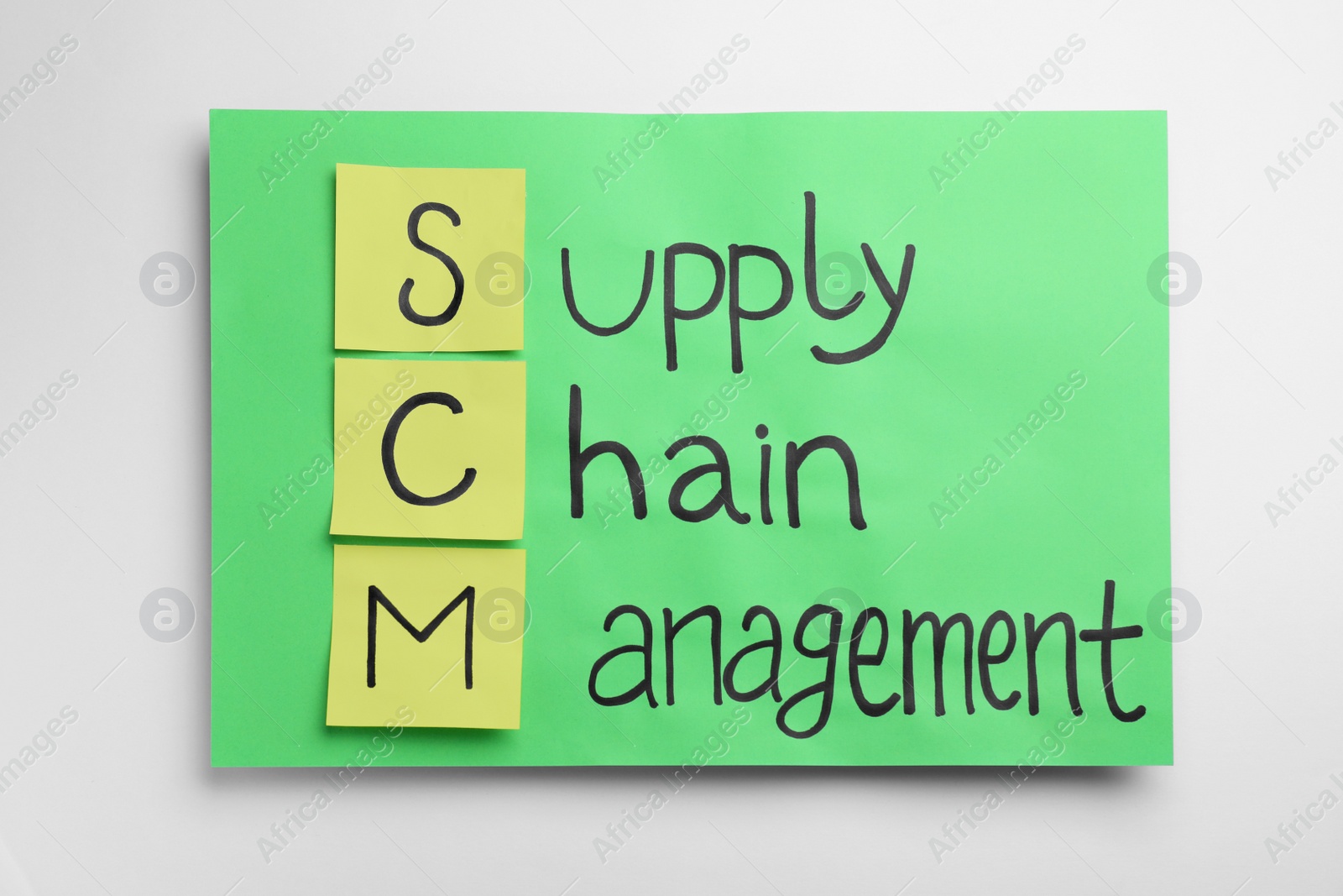 Photo of Green paper with abbreviation SCM (Supply Chain Management) on white background, top view