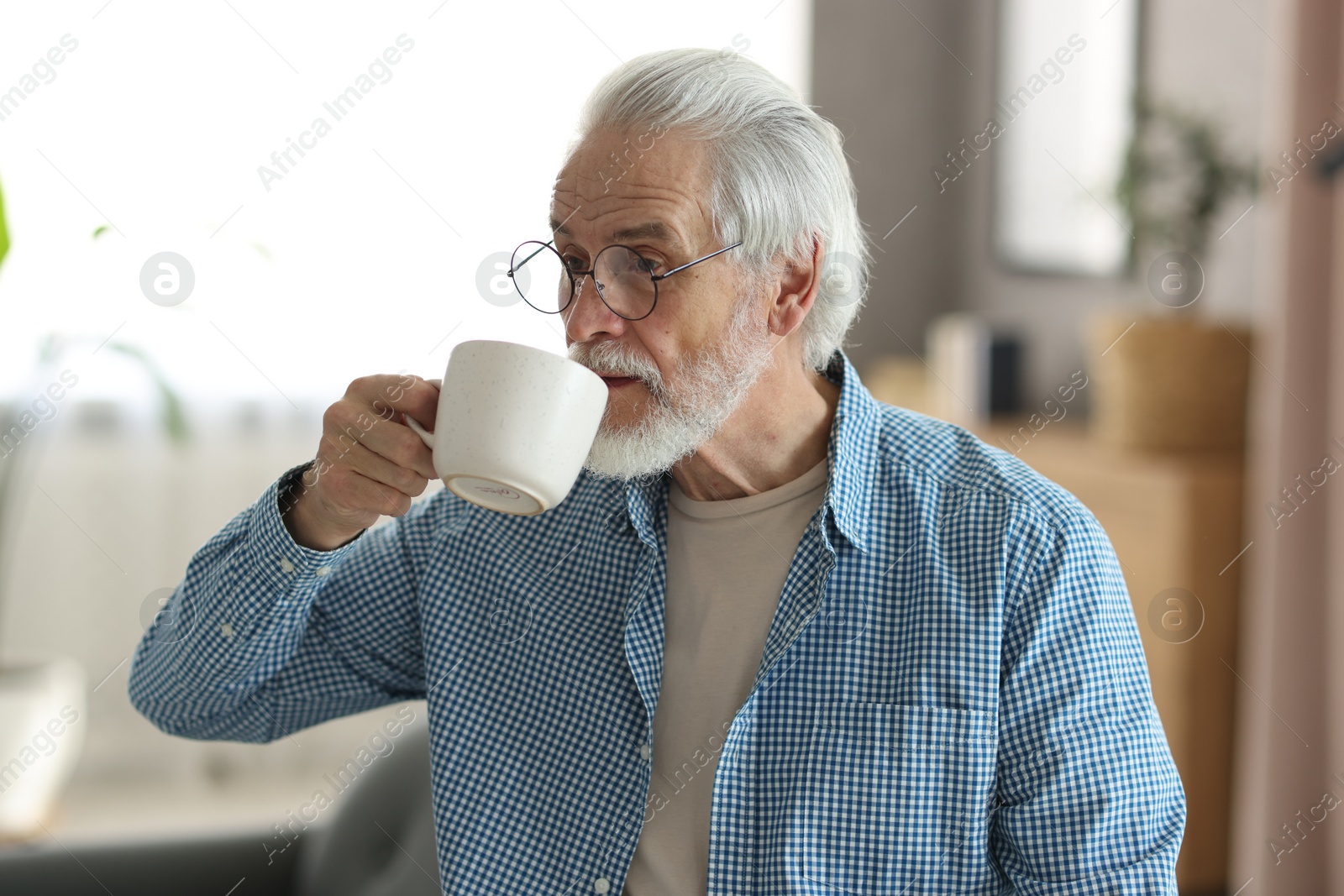 Photo of Portrait of happy grandpa with glasses and cup of drink indoors