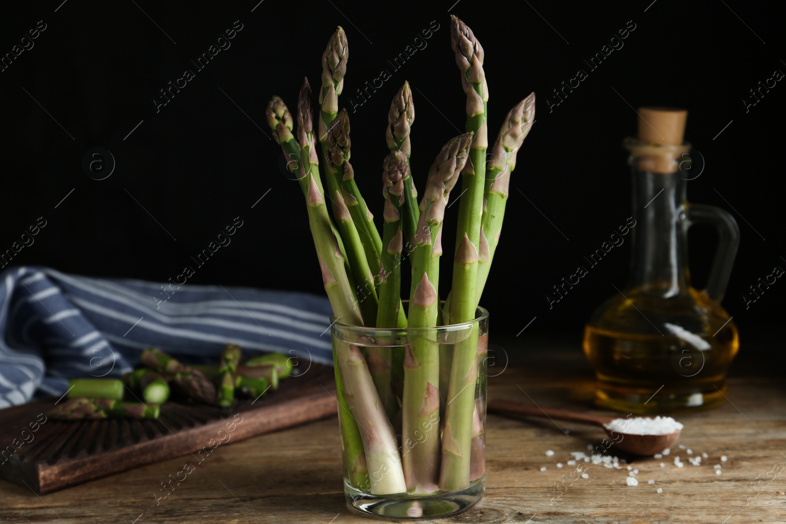 Photo of Fresh raw asparagus in glass on wooden table