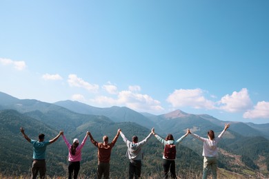 Group of people spending time together in mountains, back view. Space for text