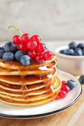 Delicious pancakes with fresh berries and syrup on table