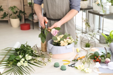 Photo of Male florist pruning rose at workplace