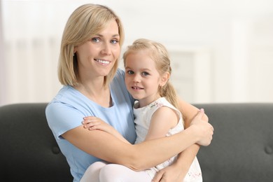 Happy mother and daughter on sofa at home