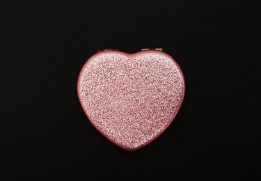 Heart shaped gold pocket mirror on black background, top view