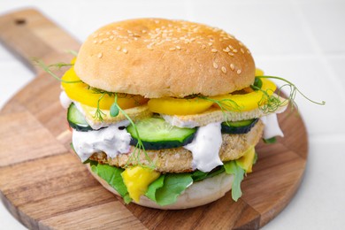 Photo of Tasty vegan burger with vegetables, sauce and patty on white background, closeup