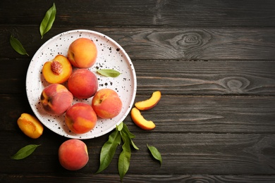 Photo of Fresh sweet peaches on black wooden table, flat lay. Space for text