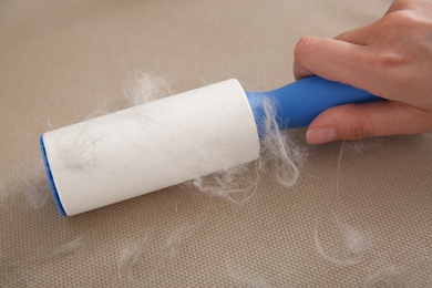 Photo of Woman removing hair from beige surface, closeup