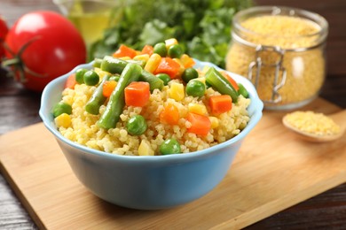 Photo of Tasty millet porridge with vegetables in bowl on wooden table, closeup