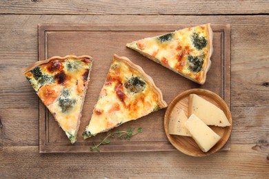 Photo of Pieces of delicious homemade quiche and ingredients on wooden table, top view