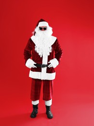 Photo of Full length portrait of Santa Claus with sunglasses on red background