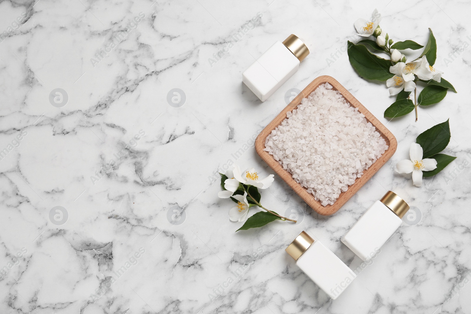 Photo of Beautiful jasmine flowers, sea salt and skin care products on white marble table, flat lay. Space for text