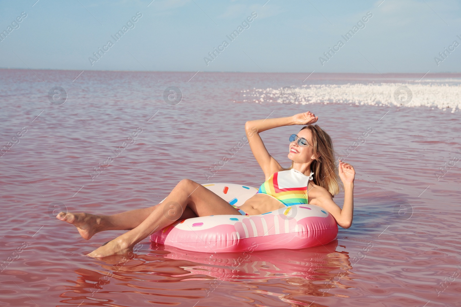 Photo of Beautiful woman on inflatable ring in pink lake