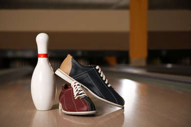 Shoes and pin on bowling lane in club. Space for text