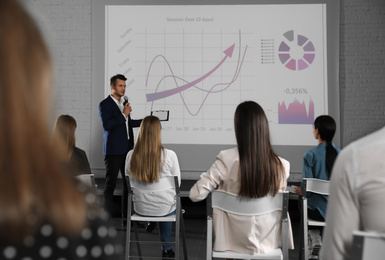 Photo of Male business trainer giving lecture in conference room with projection screen