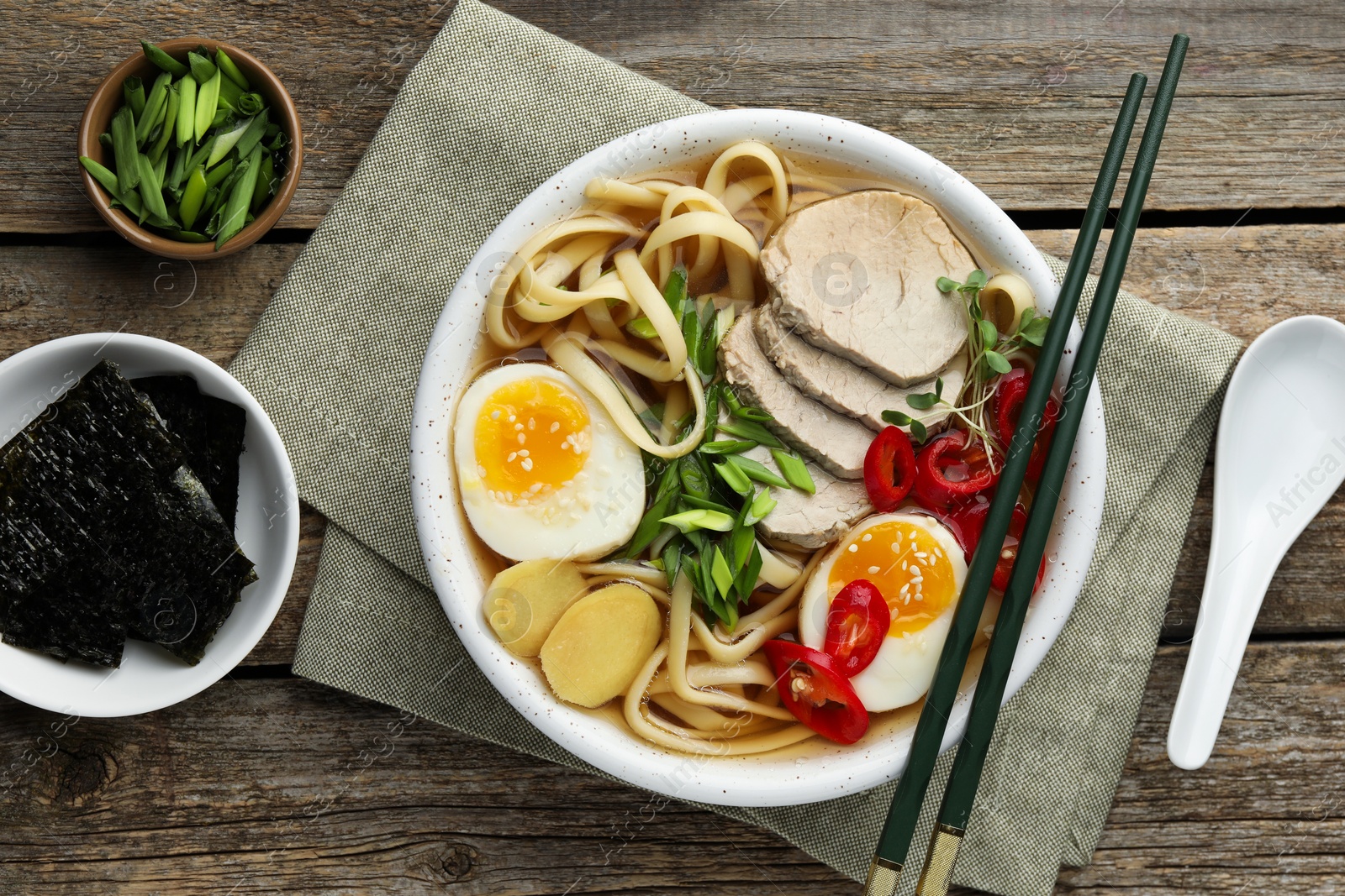 Photo of Delicious ramen in bowl served on wooden table, flat lay. Noodle soup