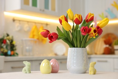 Photo of Bouquet of tulips and Easter decorations on white table indoors, closeup