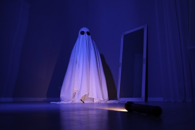 Photo of Creepy ghost. Woman covered with sheet in blue light, low angle view