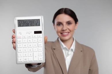 Photo of Smiling accountant against grey background, focus on calculator
