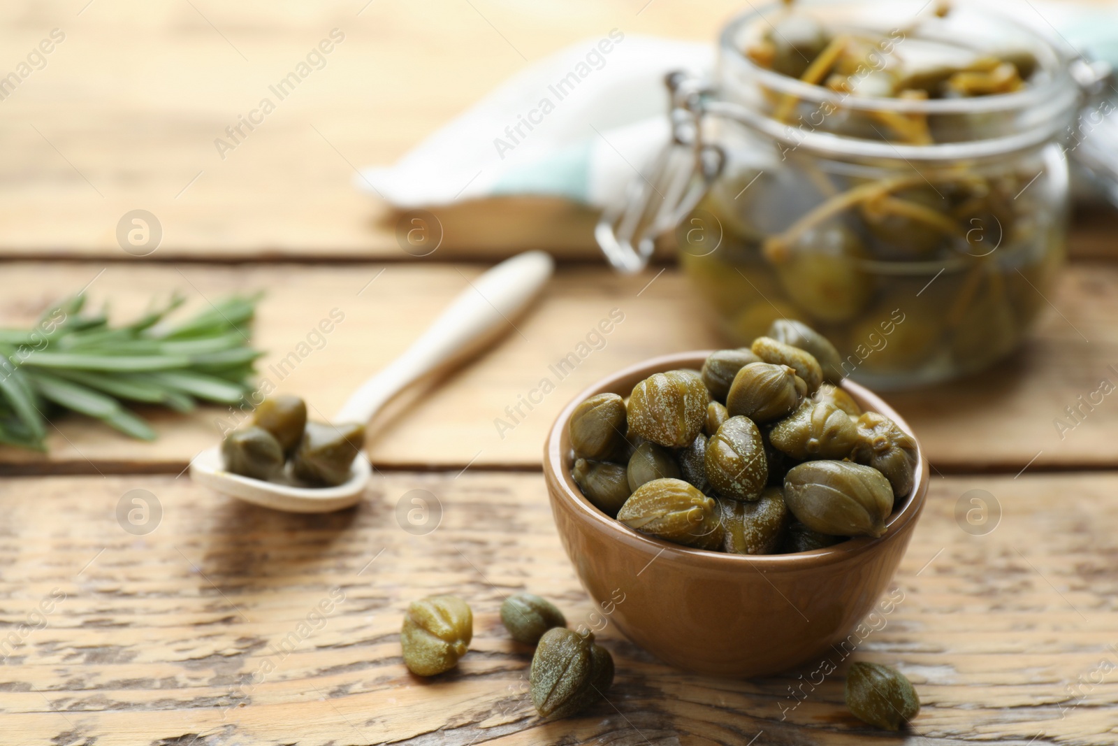 Photo of Delicious pickled capers on wooden table, space for text