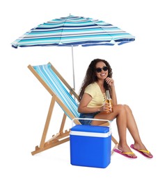 Photo of Happy young African American woman with bottle of beer resting in deck chair near cool box on white background