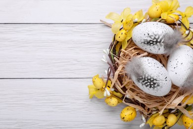 Photo of Festively decorated Easter eggs on white wooden table, top view. Space for text