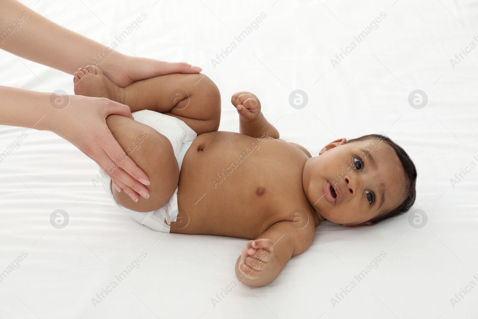 Photo of Mother and her cute child on white bed. Baby massage and exercises