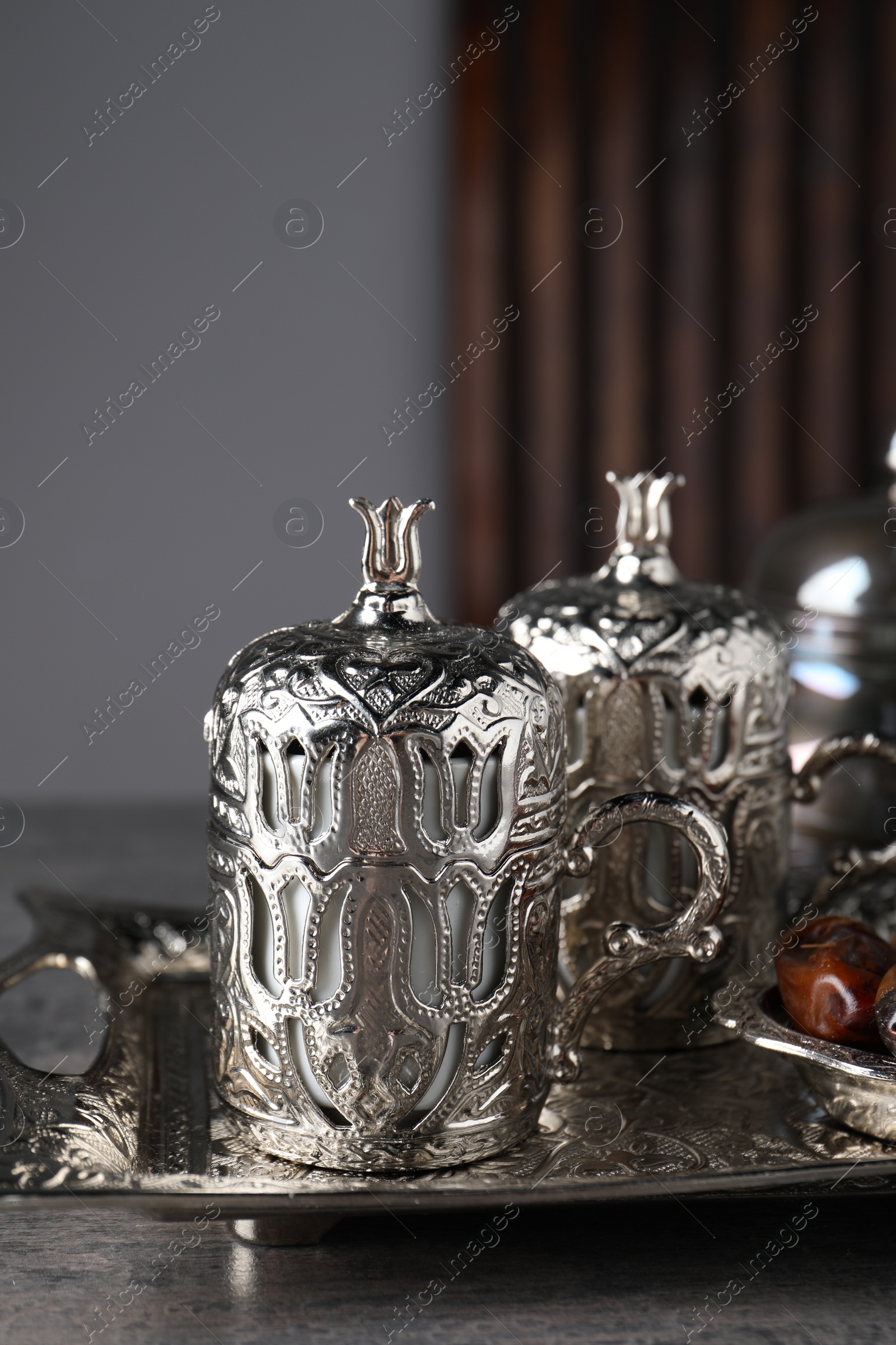 Photo of Tea and date fruits served in vintage tea set on grey textured table, closeup