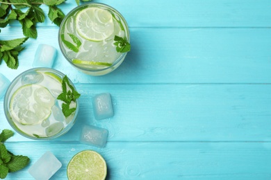 Flat lay composition of cocktail with vodka, ice and lime on blue wooden table. Space for text