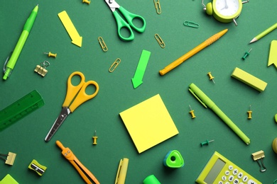 Photo of Bright school stationery on green background, flat lay