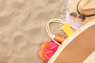 Photo of Stylish bag with beach accessories on sand, flat lay. Space for text