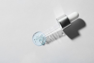 Pipette with cosmetic serum on white background, top view