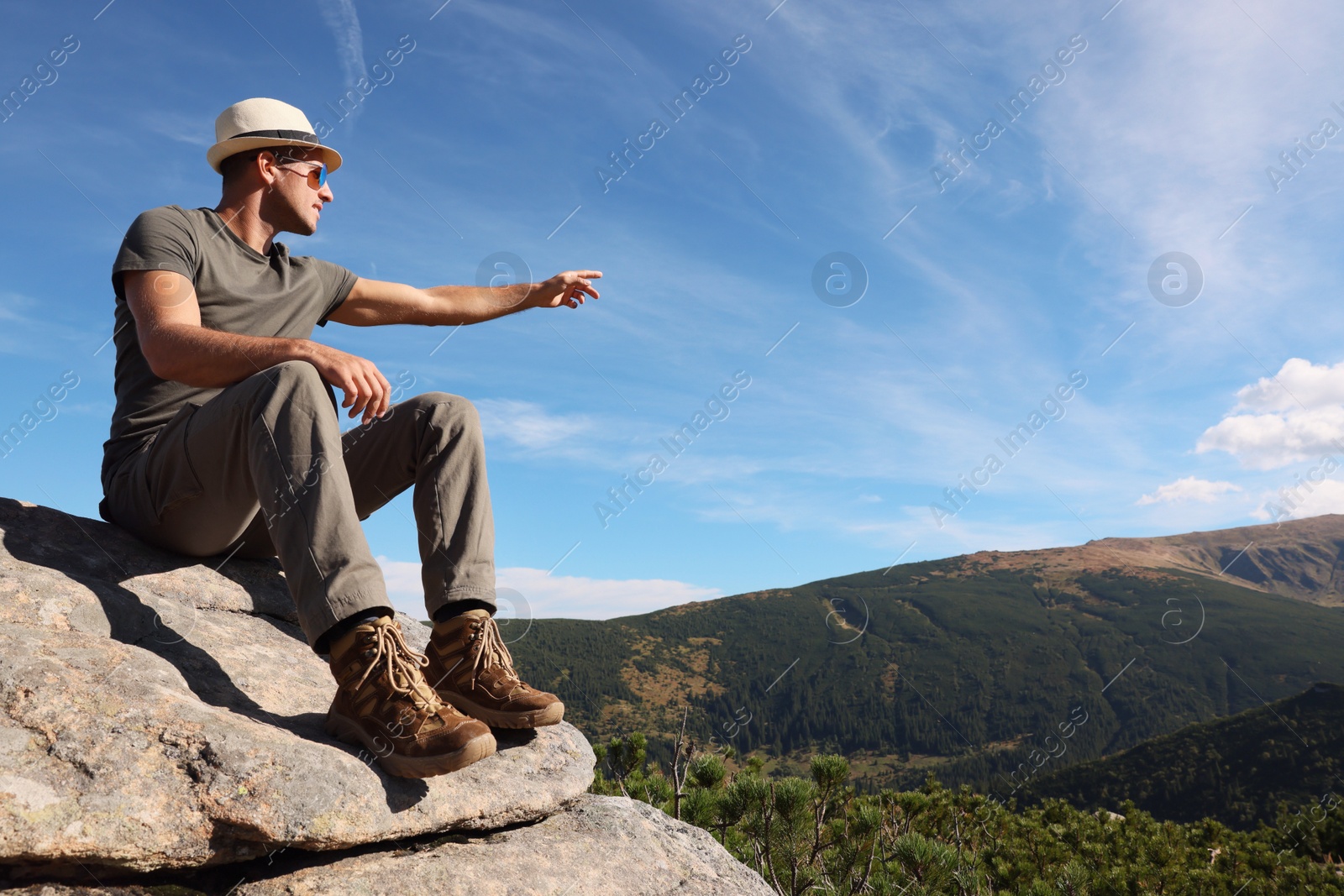 Photo of Man enjoying picturesque view on cliff in mountains. Space for text