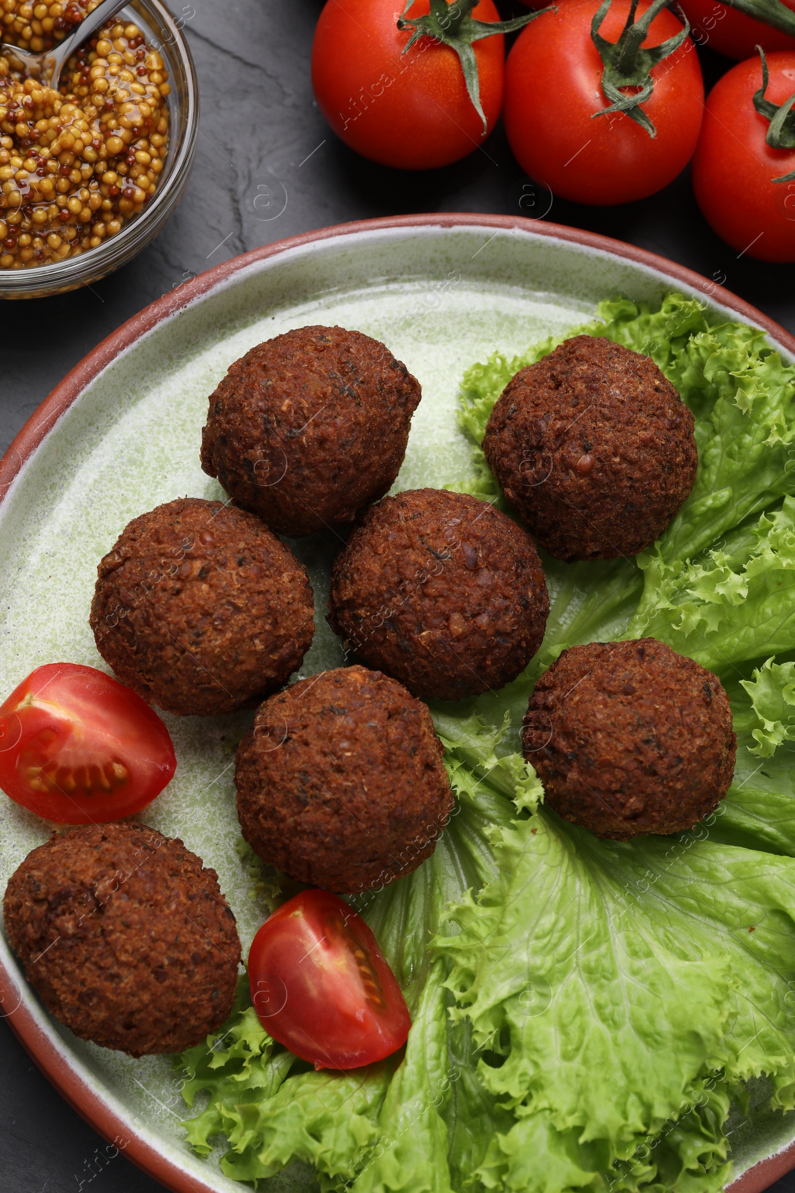 Photo of Delicious falafel balls, tomatoes, lettuce and grain mustard on table, flat lay. Vegan meat products