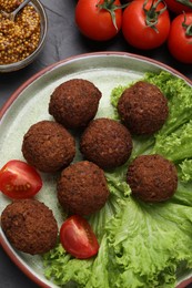 Photo of Delicious falafel balls, tomatoes, lettuce and grain mustard on table, flat lay. Vegan meat products