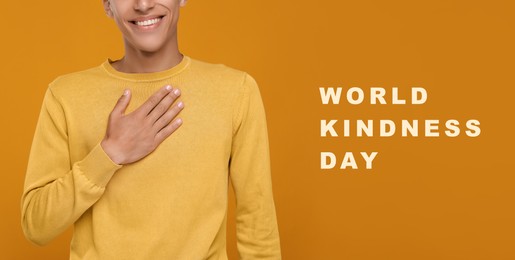 World Kindness Day. Grateful man pressing hand to chest on orange background, closeup. Banner design