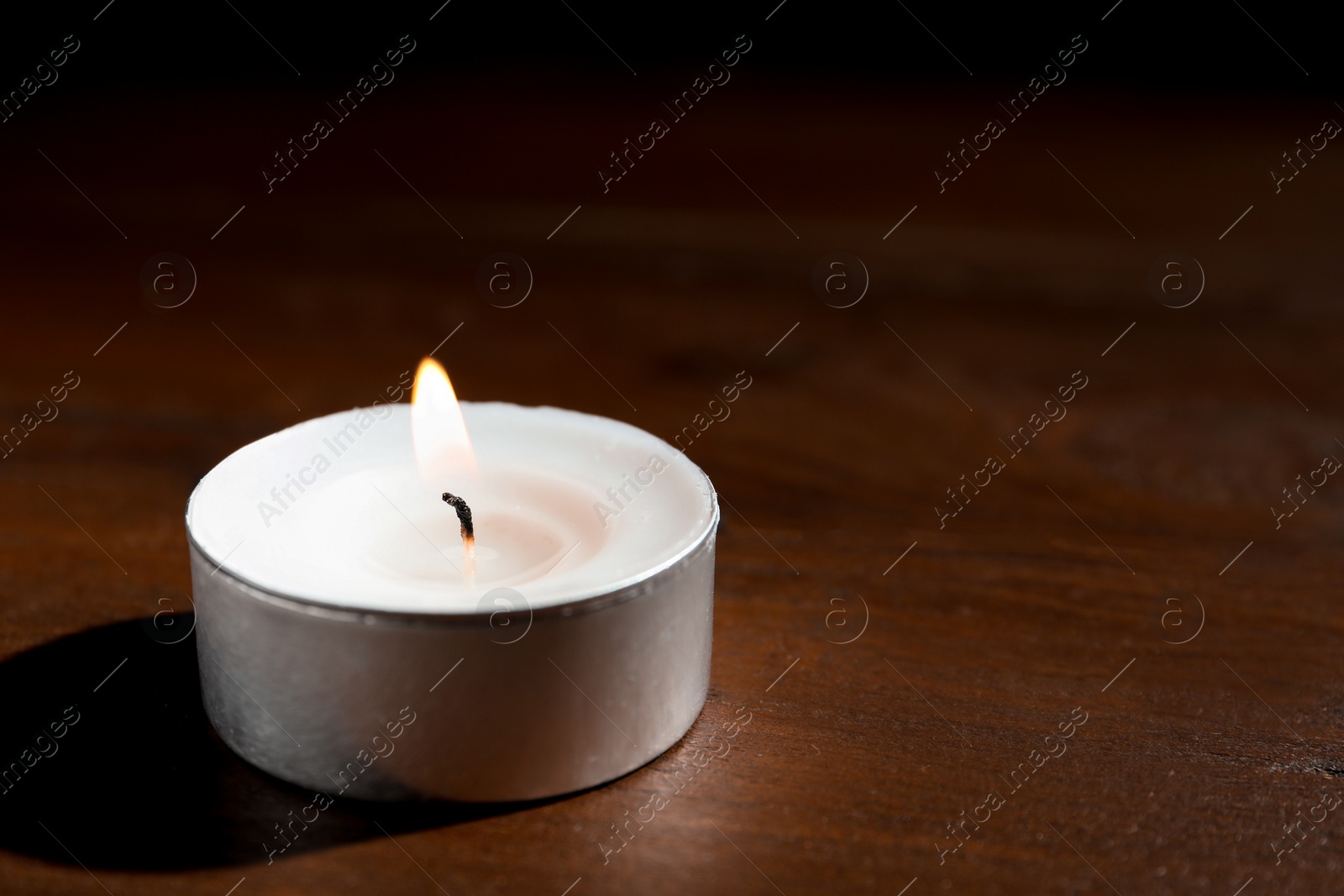 Photo of Wax candle burning on wooden table