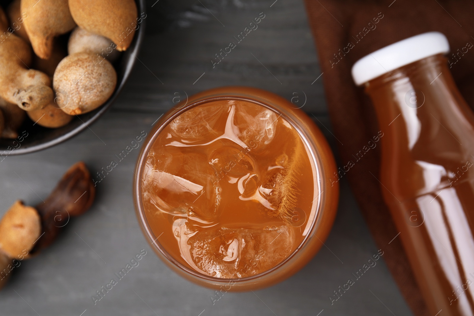 Photo of Tamarind juice and fresh fruits on grey wooden table, flat lay