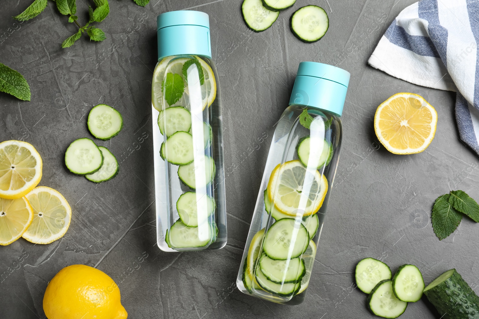 Photo of Bottles of refreshing water with cucumber, lemon and mint on black table, flat lay