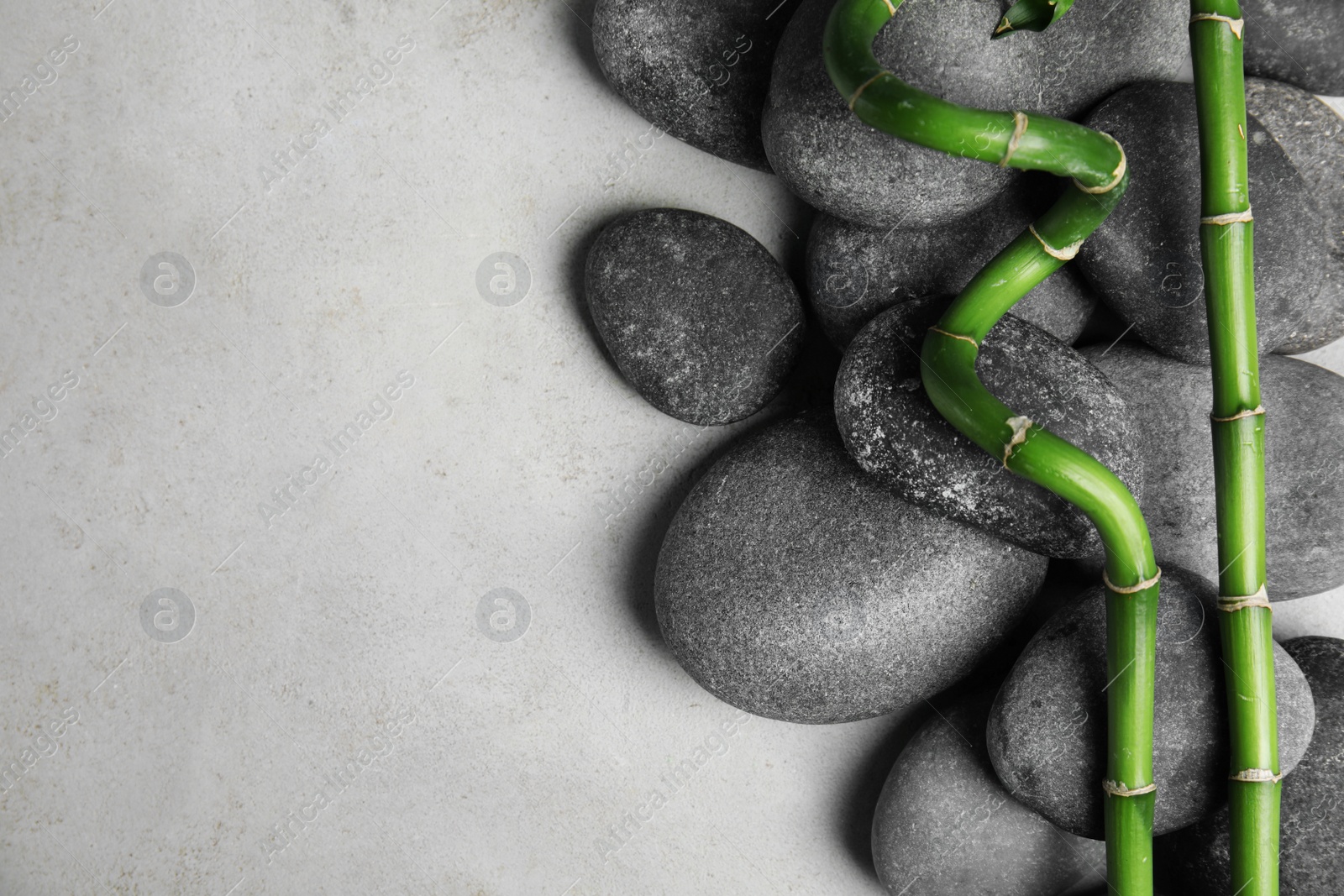 Photo of Zen stones and bamboo on grey background, top view with space for text