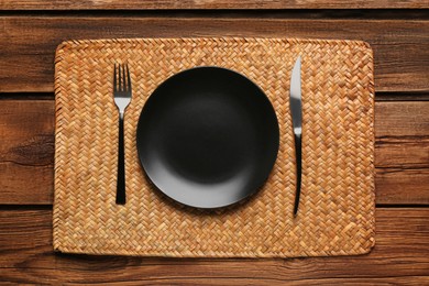 Photo of Clean plate and shiny silver cutlery on wooden table, flat lay