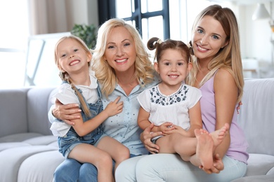 Photo of Young woman with mature mother and little daughters in living room