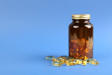 Jar with vitamin capsules on blue background, space for text