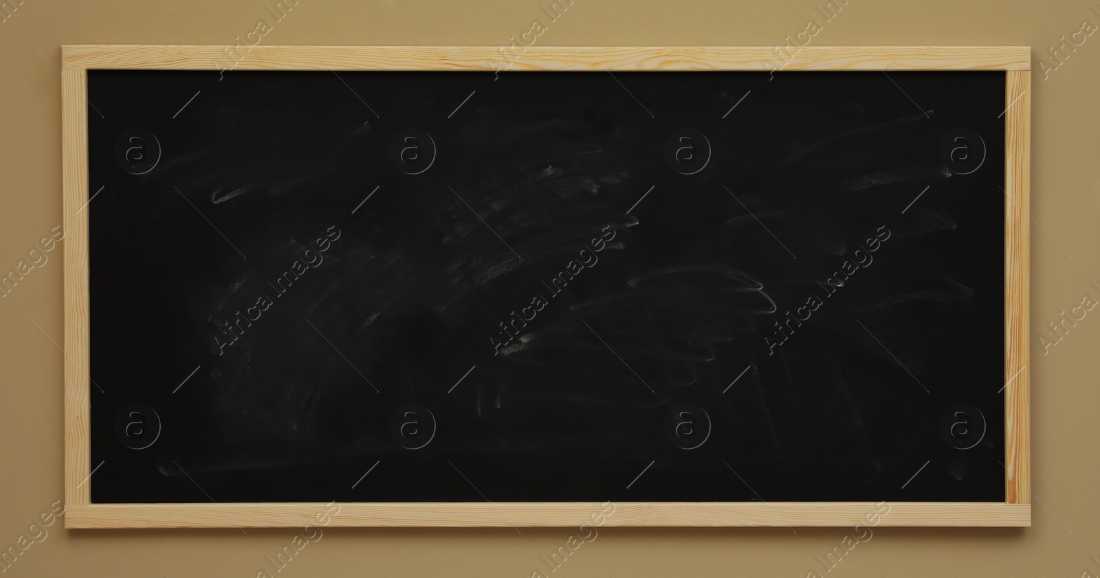 Photo of Dirty black chalkboard hanging on beige wall