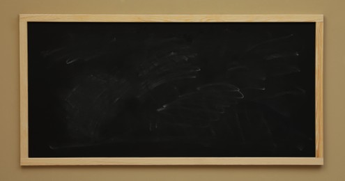 Photo of Dirty black chalkboard hanging on beige wall