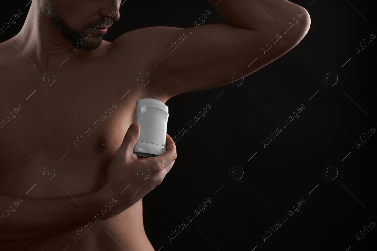 Photo of Man applying deodorant on black background, closeup. Space for text