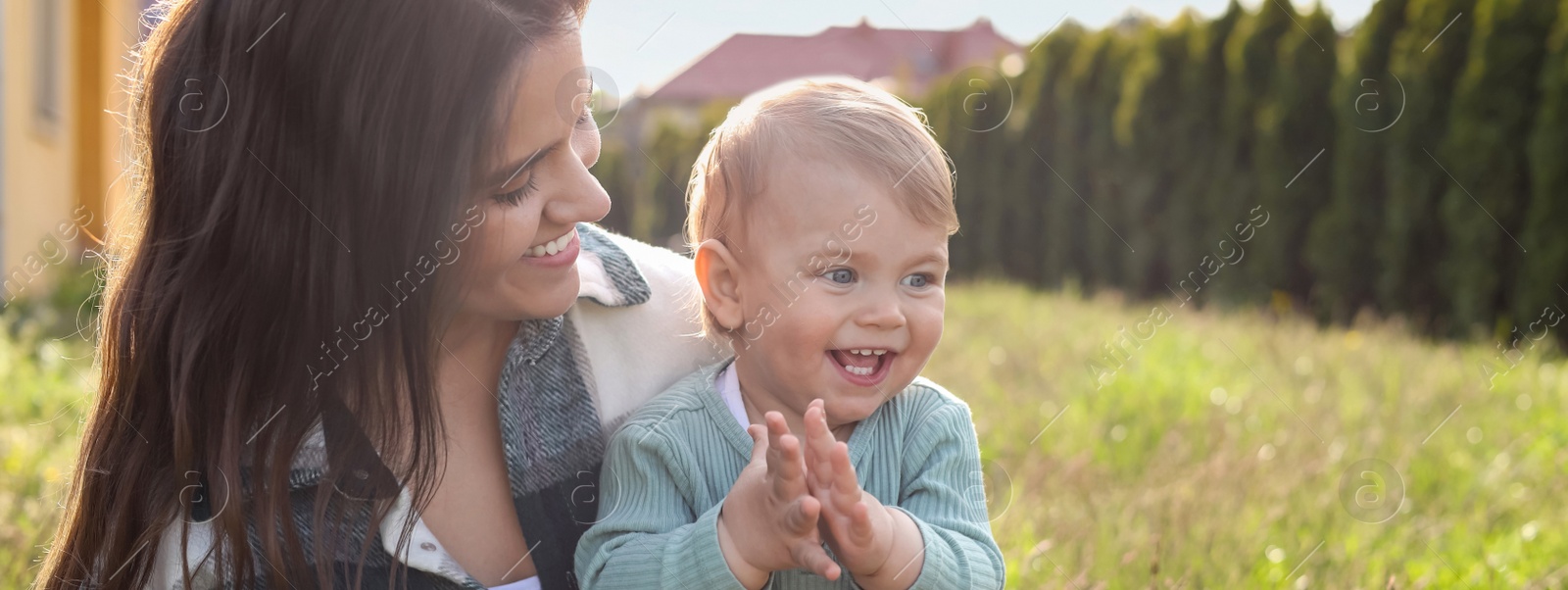 Image of Happy mother with her cute baby at backyard on sunny day, space for text. Banner design