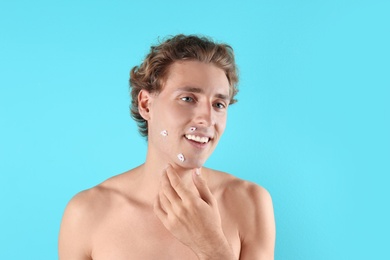 Young man with face hurt while shaving on color background