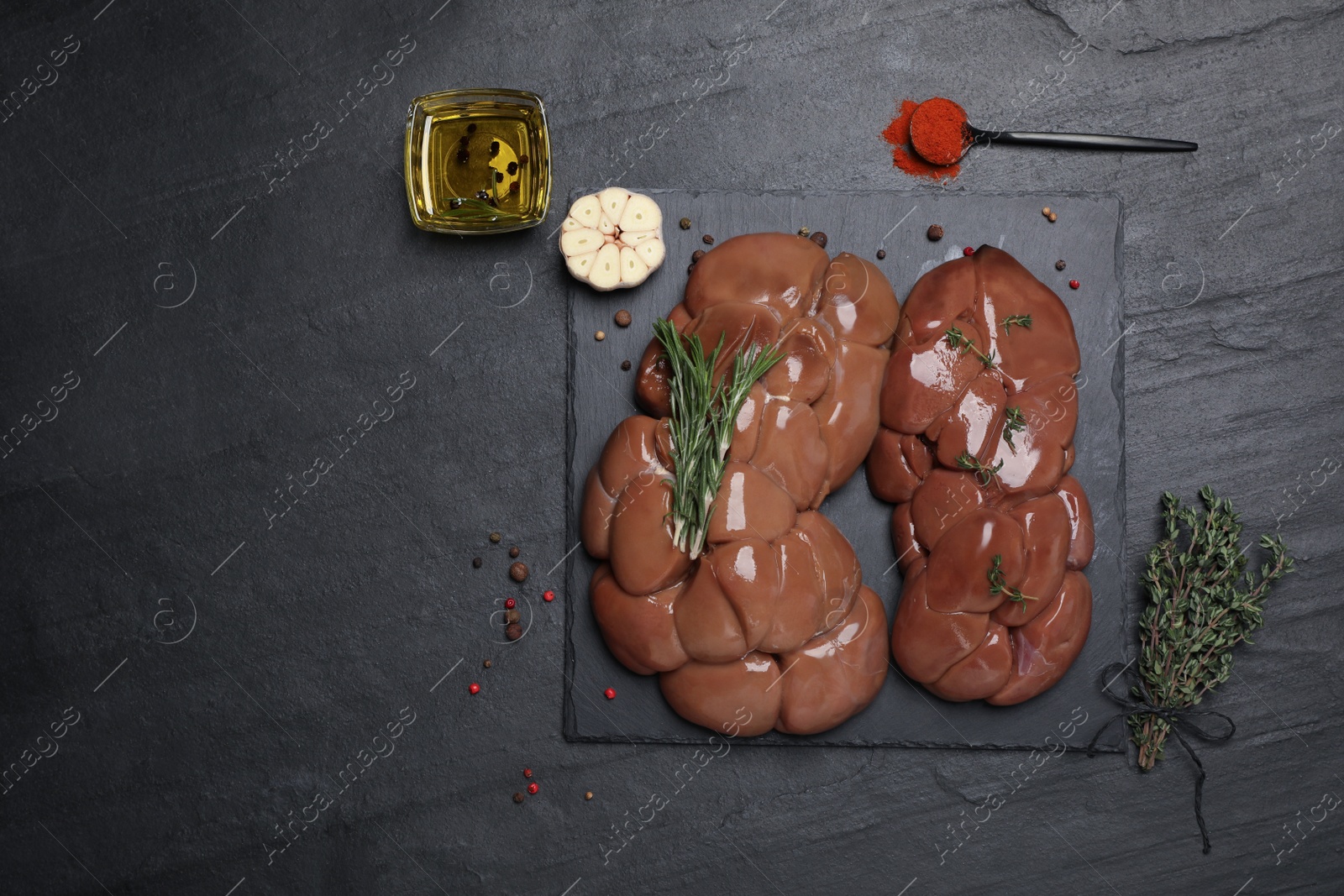 Photo of Fresh raw kidneys with seasonings on black table, flat lay. Space for text